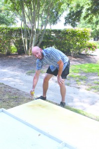 Macky James bends down to spray paint a board at the Board Paint Day last Friday