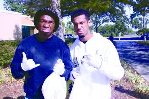 Nigel Cribbs and Andre’ Phillips hold up their Greek signs in the Quad and smelling the trash they picked up at Saturday’s clean-up.  